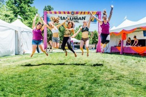 five women jumping in front of the Hanuman Festival sign